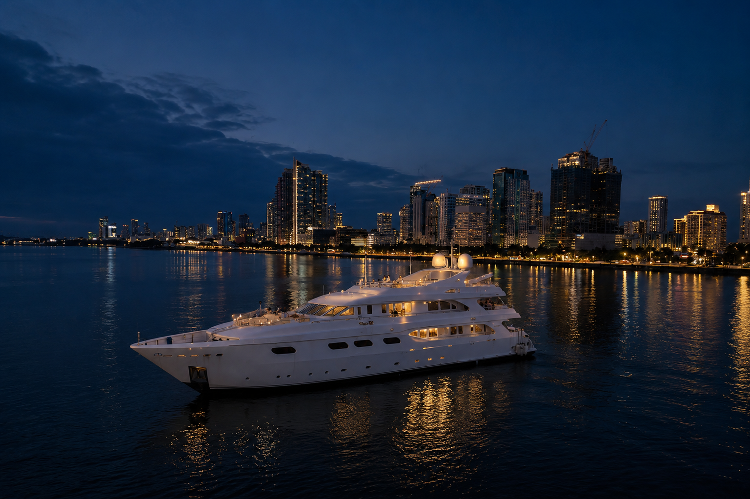 Happy Life Yacht docked on Manila Bay at night, with the city skyline behind
